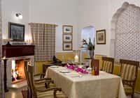 Dining table laid beside a lit fireplace