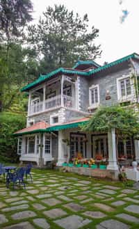 The villa from the garden path with blue chairs on the grass