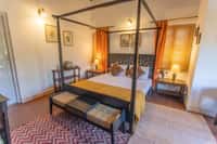 Magpie room with dark four poster bed and gold curtains
