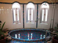 Round mosaic tiled sunken bath below arched windows