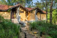 A bungalow at Kanha Earth Lodge, mud plaster and tiled roof among the trees