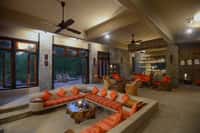The lounge at Kanha Earth Lodge, sunken seating around a tree-trunk table