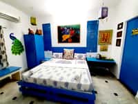 Art-themed bedroom in blue with Indian paintings and a peacock figure