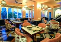 The rooftop restaurant at Dev Mahal at dusk, arches open to the Jaipur skyline