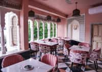 Pink arches and floral chairs in the rooftop restaurant at Dev Mahal, Jaipur