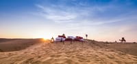 Private Dune Dinner table set on the sands at sunset with a camel approaching, Dhora Desert Resort & Spa, Shekhala