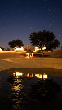 Campfire and tents reflected in the pond at night, Dhora Desert Resort & Spa, Shekhala