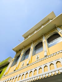 Looking up at the arched windows and carved parapet of the facade, Diwan House, Agra