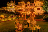 Guests around a bonfire on the lawn below the illuminated fort at night, Fort Dhariyawad, Dhariyawad