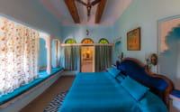 Blue-themed heritage bedroom with window seats and stained-glass arches, Fort Dhariyawad, Dhariyawad