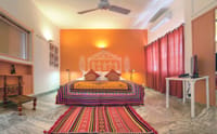 Banni room with orange feature wall, Kachchh-style mural and mirrored bedspread, Haveli Hauz Khas, New Delhi