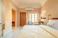 Bedroom in warm lime plaster with teak door and garden-facing window, Niravi, Jaipur