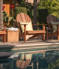 Wooden loungers and rolled towels at the pool edge among canna lilies, Niravi, Jaipur