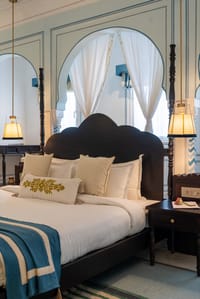 Four-poster bed beneath scalloped blue-and-white arches in a suite, Padmaa, Jaipur