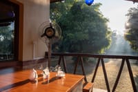 Morning tea on a verandah table overlooking misty lawns, Soulacia Hotel & Resort, Kanha