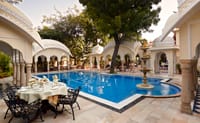 Poolside dining table beside the arcaded pool