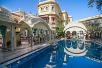Swimming pool with sun loungers under trees