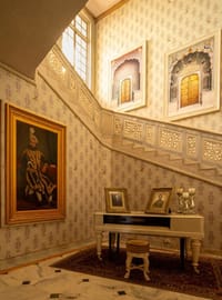 The staircase hall, with a maharaja’s portrait, a piano and family photographs