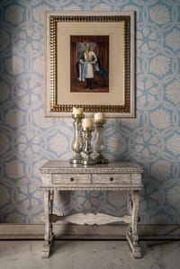 A portrait above a carved console and mercury-glass candlesticks