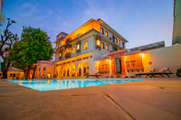 Pool and painted haveli buildings at dusk