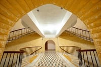 Golden sandstone atrium with twin curved staircases