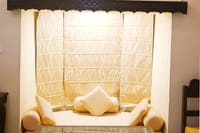 Cushioned window lounge nook with draped canopy
