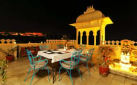 Rooftop restaurant table at night with lit chhatri and fort view