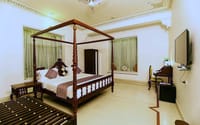 Four-poster bed in a haveli room with window drapes