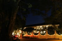 The Malabar House exterior at night, white gateposts and facade lit beneath old trees on Parade Road