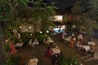 Evening dinner tables under the trees on the patio of The Malabar House, seen from above