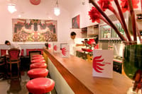 Divine wine lounge at The Malabar House: timber bar, red stools and a large painted mural