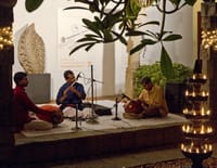 Carnatic musicians performing on the patio stage at The Malabar House beside a brass oil lamp