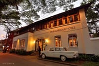 Old Harbour Hotel facade at evening with a vintage white car parked at the arched entrance