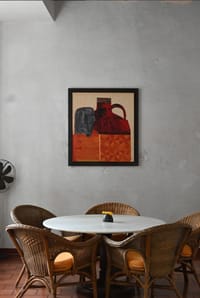 Dining corner at Old Harbour Hotel: cane chairs around a round marble-topped table below a framed artwork