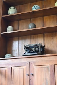 Teak cabinet at Old Harbour Hotel with old ceramic jars and an antique typewriter