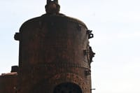 Rusted riveted iron boiler standing in the grounds of Old Harbour Hotel