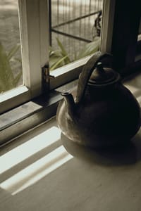 Brass kettle on a window sill at Old Harbour Hotel with slatted light