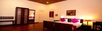 Tea Bungalow, Fort Kochi: heritage room with polished wood floor, wardrobe, bed with pink cushions and a brass lamp