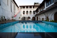 The Old Courtyard Hotel, Fort Kochi: the swimming pool in the inner courtyard with the arched white facade and wooden deck behind