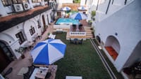 The Old Courtyard Hotel courtyard seen from an upper floor: lawn, blue and white umbrellas, pool and timber deck