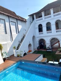 The pool at The Old Courtyard Hotel with the external staircase and two tiers of arches above