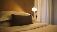 Bed detail with embroidered cushion and reading lamp in a Bastion Room