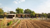 Low villa building across a ploughed farm field