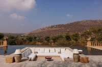 Infinity pool with white daybeds facing hills