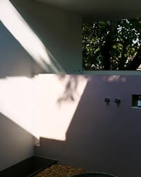 Open-to-air bathroom wall with tree shadows