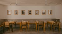 Cafe tables and bench under a row of framed prints