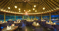 Restaurant laid for dinner under a thatched dome