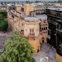 The palace roofline and jharokha windows seen from above, village rooftops beyond