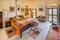 Suite bedroom with a carved wooden bed, framed photographs on the walls and doors open to a terrace