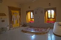 Bathroom with a sunken tub, carved stone doorway and twin arched window seats